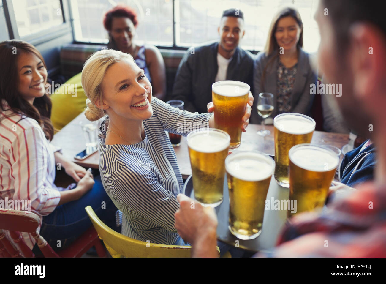 Bartender serving beers on tray to friends in bar Stock Photo