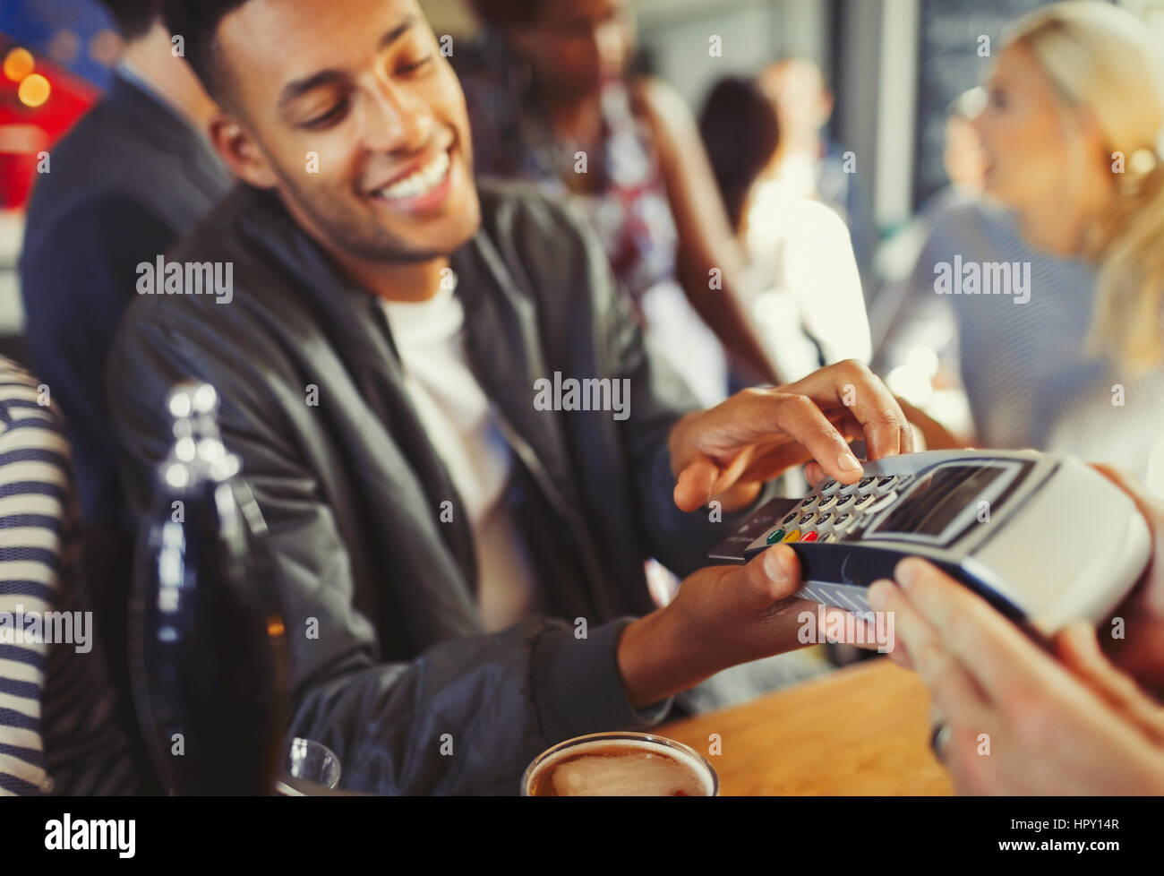 Smiling man paying bartender using credit card reader at bar Stock Photo