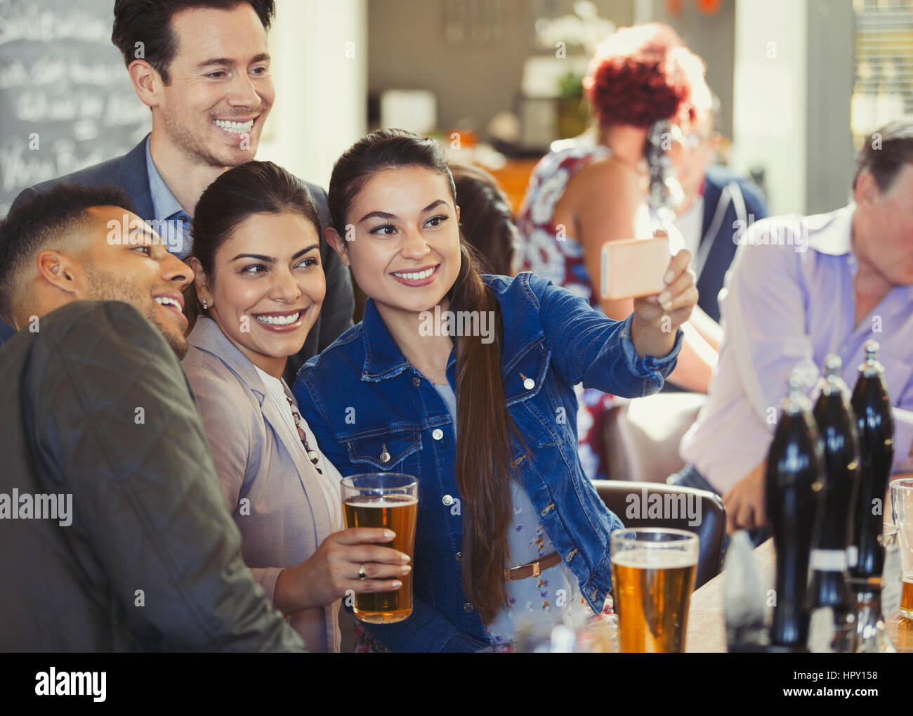 Playful friends drinking beer and taking selfie with camera phone at bar Stock Photo