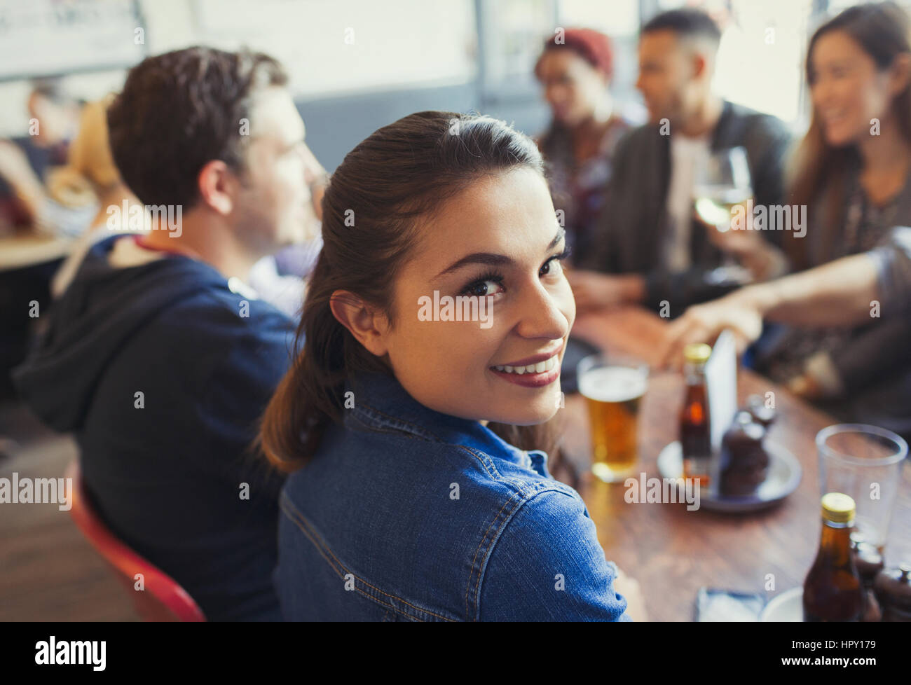 Portrait smiling woman drinking beer with friends at table in bar Stock Photo
