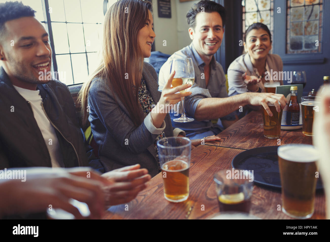 Friends drinking beer and wine and talking at table in bar Stock Photo