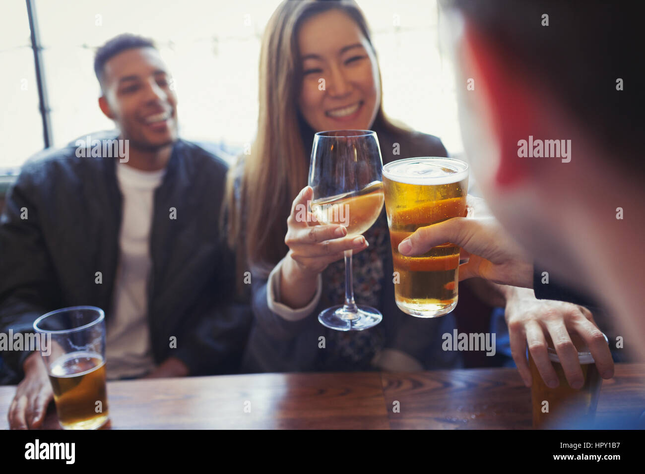 Friends celebrating, toasting beer and wine at table in bar Stock Photo