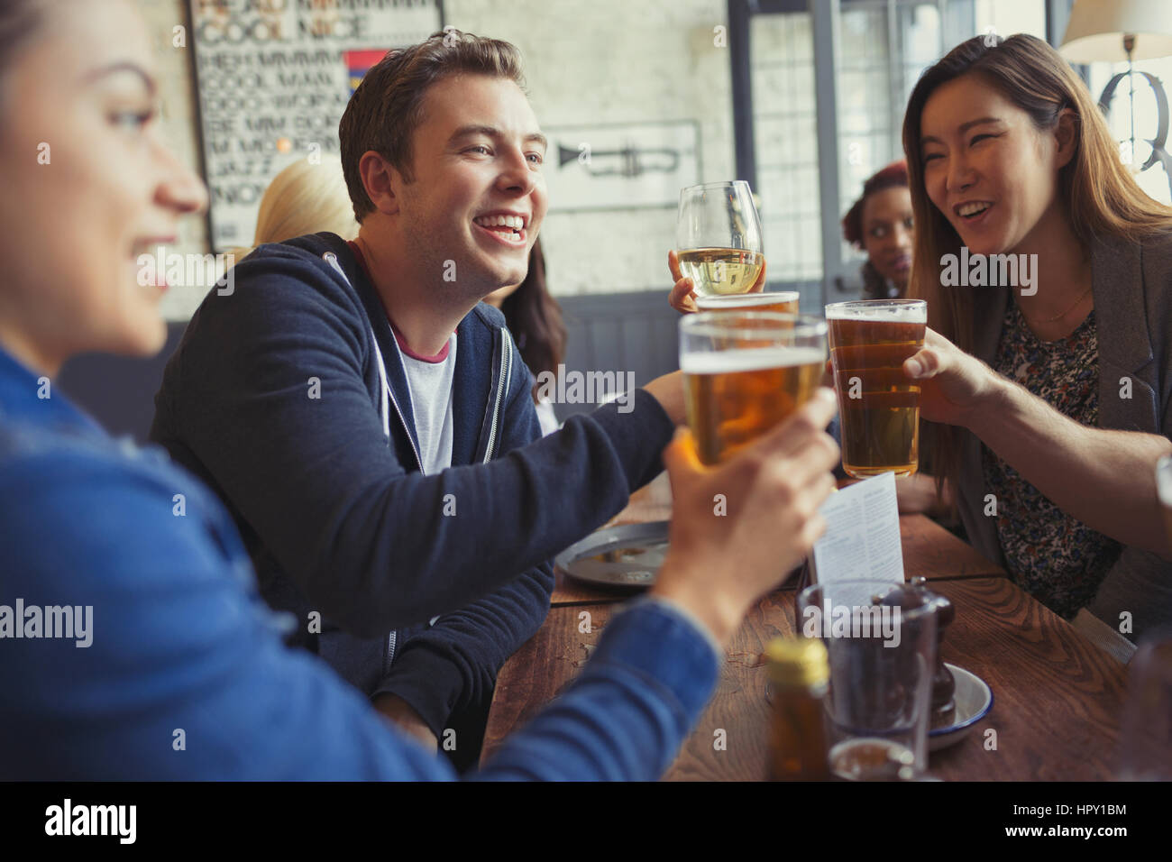 Friends celebrating, toasting beer and wine glasses at table in bar Stock Photo