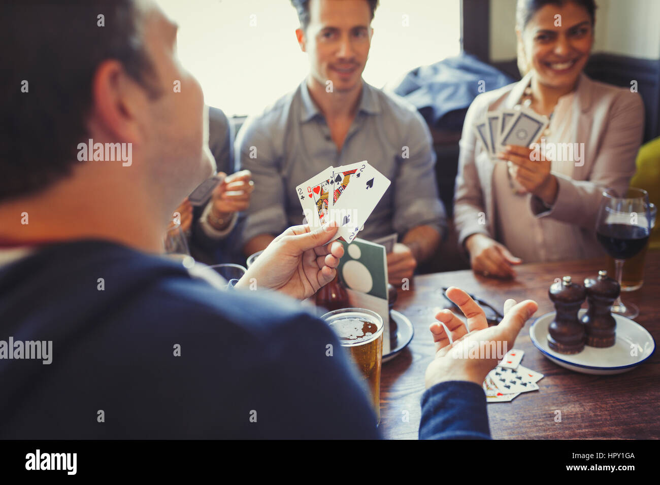 Friends playing poker and drinking beer and wine at table in bar Stock Photo