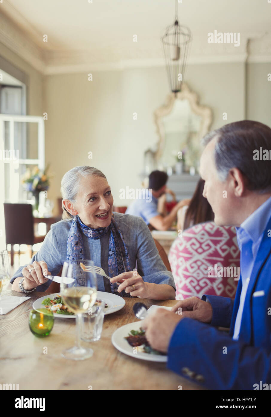 Senior couple talking and dining at restaurant table Stock Photo