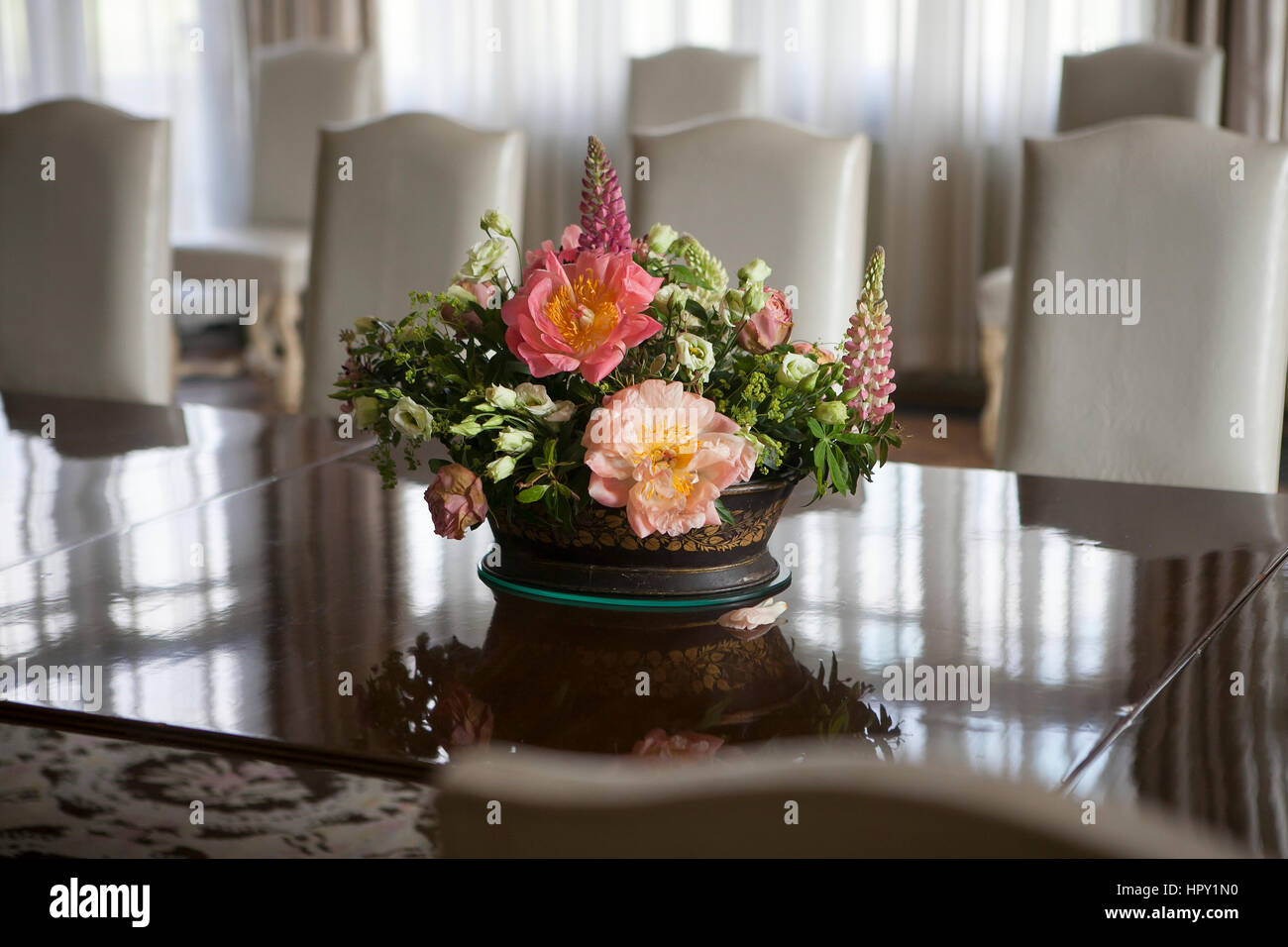 delicate bouquet of anemones, lilies, lupine, freesia stands on a glass table in the English interior Stock Photo
