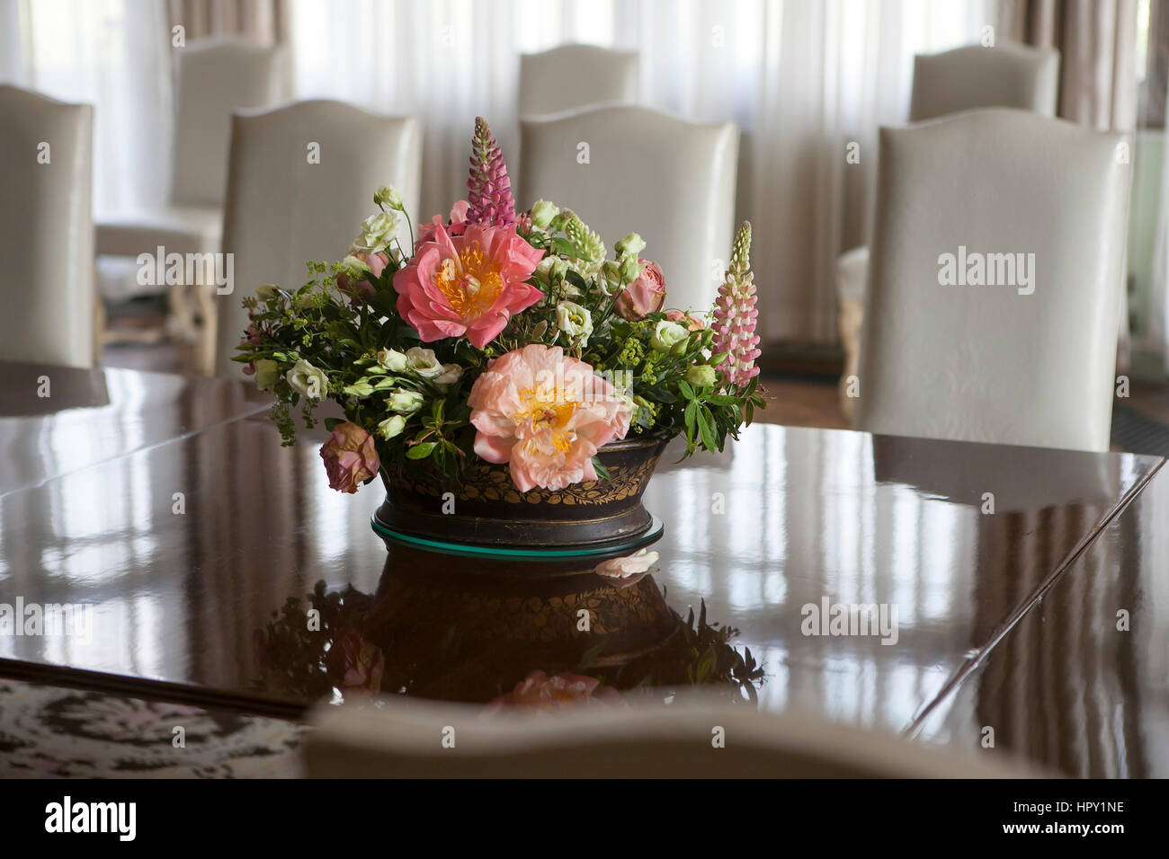 delicate bouquet of anemones, lilies, lupine, freesia stands on a glass table in the English interior Stock Photo