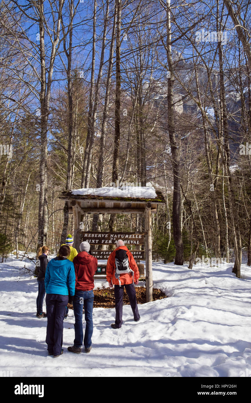 Walkers looking a sign for Reserve Naturelle de Sixt Fer A Cheval below Pic de Tenneverge in Le massif du Giffre in French Alps. Samoens, France Stock Photo