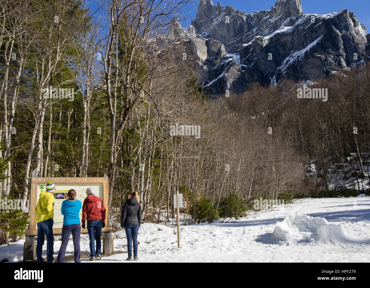 Walkers reading information board in Reserve Naturelle de Sixt Fer A Cheval below Pic de Tenneverge in Le massif du Giffre in French Alps. France Stock Photo