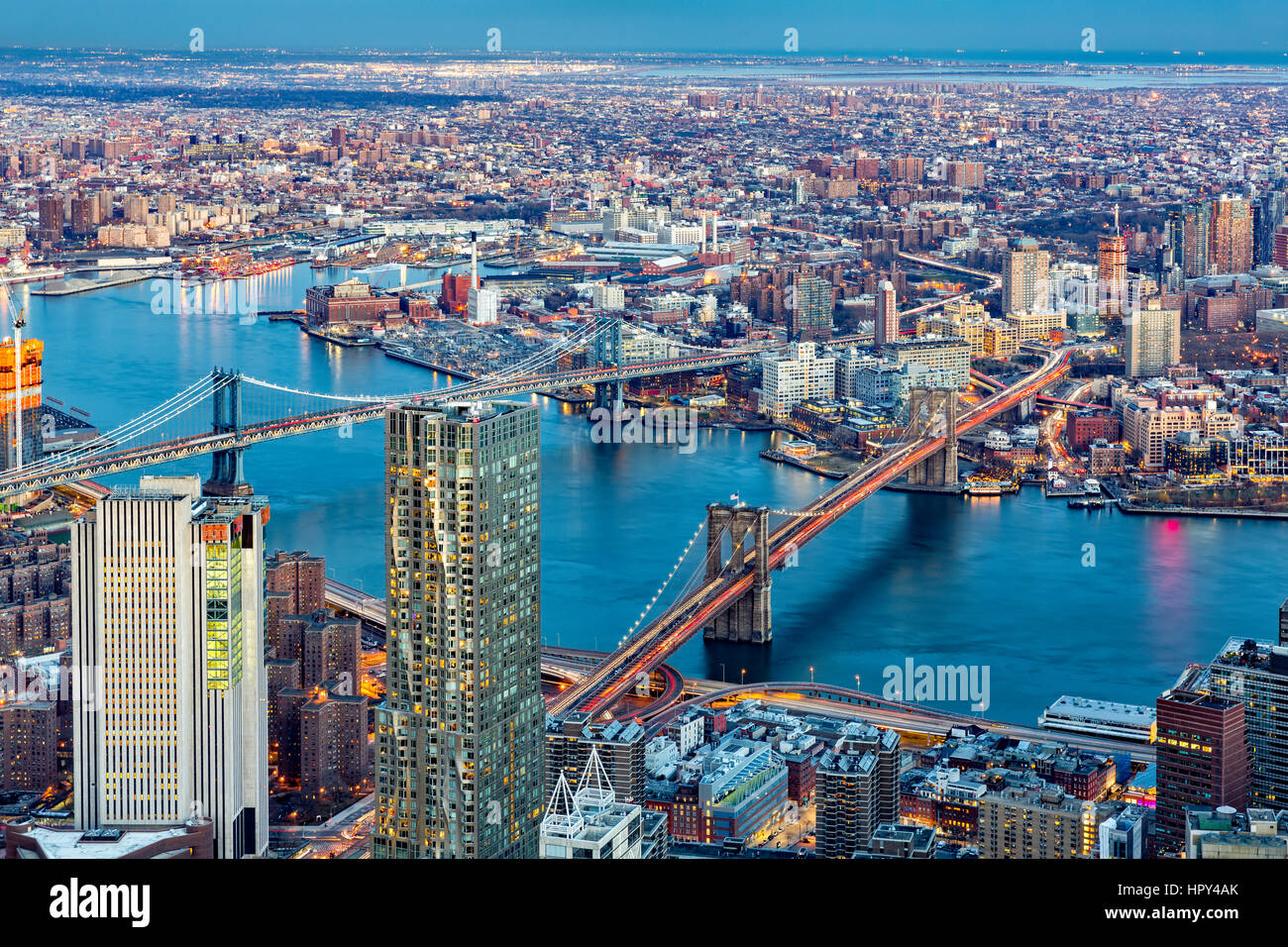 Brooklyn and Manhattan bridges span East River at dusk, between Manhattan island and Brooklyn
