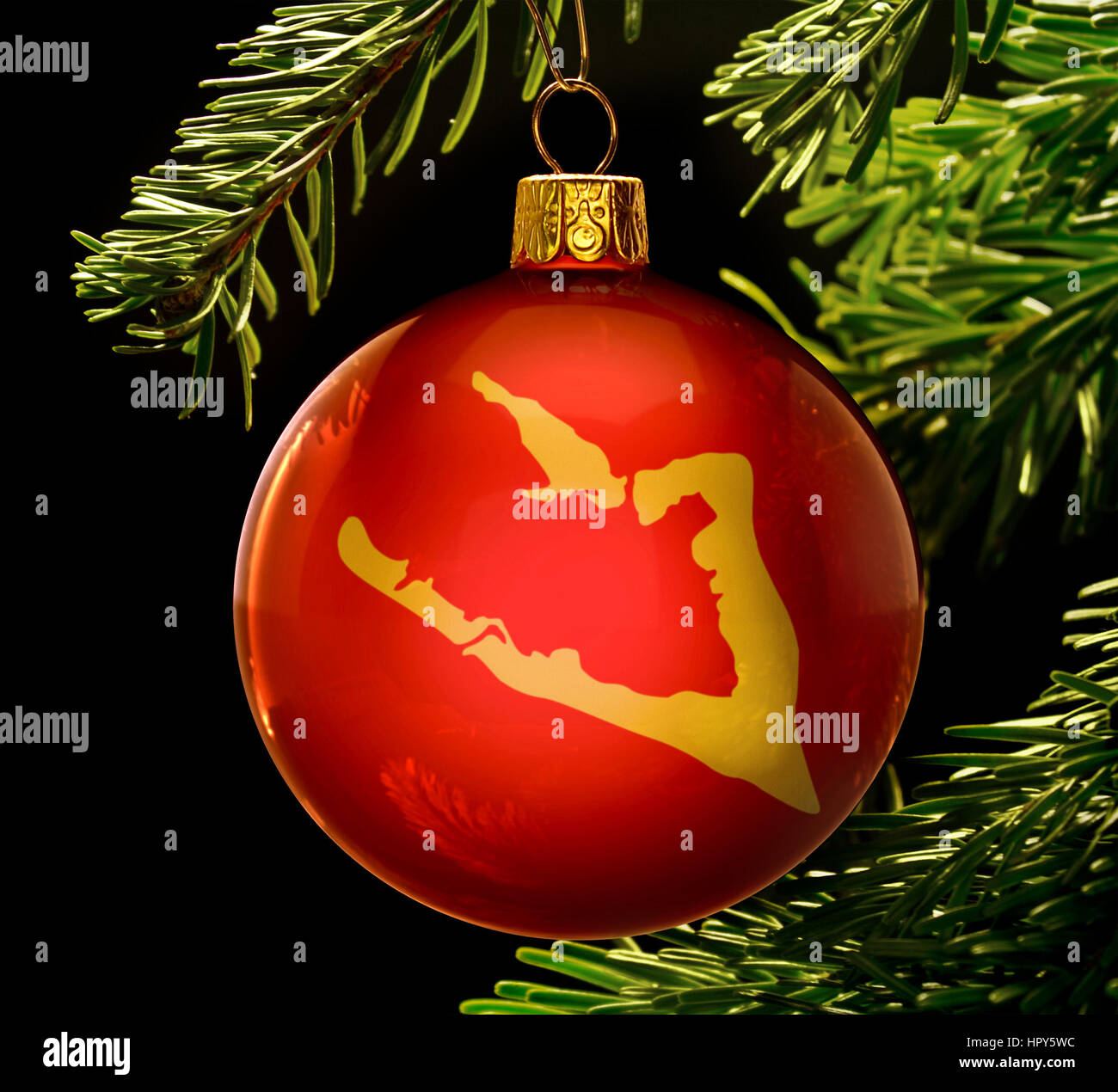 A red bauble with the golden shape of  Wake Island hanging on a christmas tree isolated on black.(series) Stock Photo