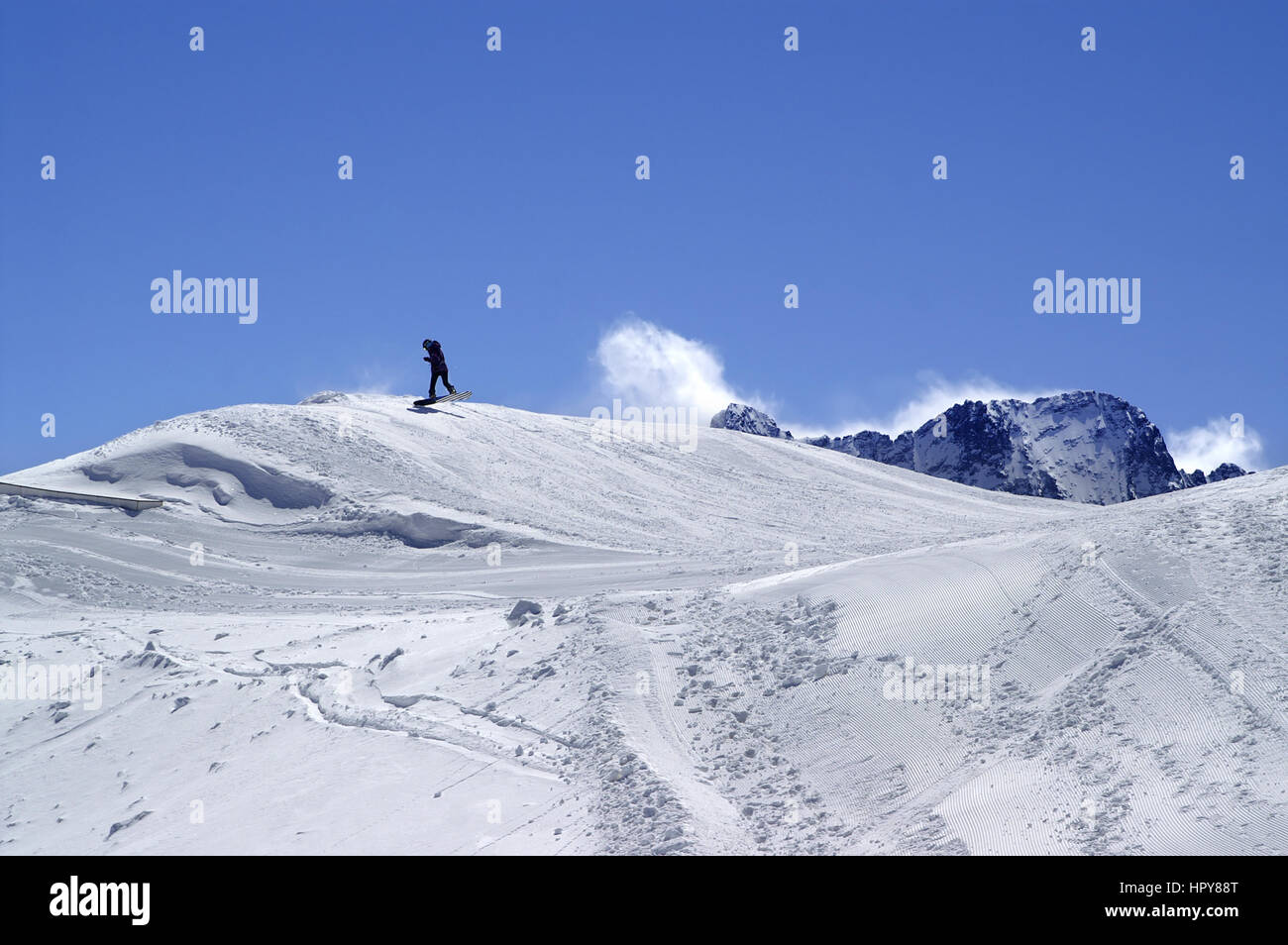 Snowboarder in terrain park at ski resort on sun winter day. Caucasus Mountains, region Dombay. Stock Photo