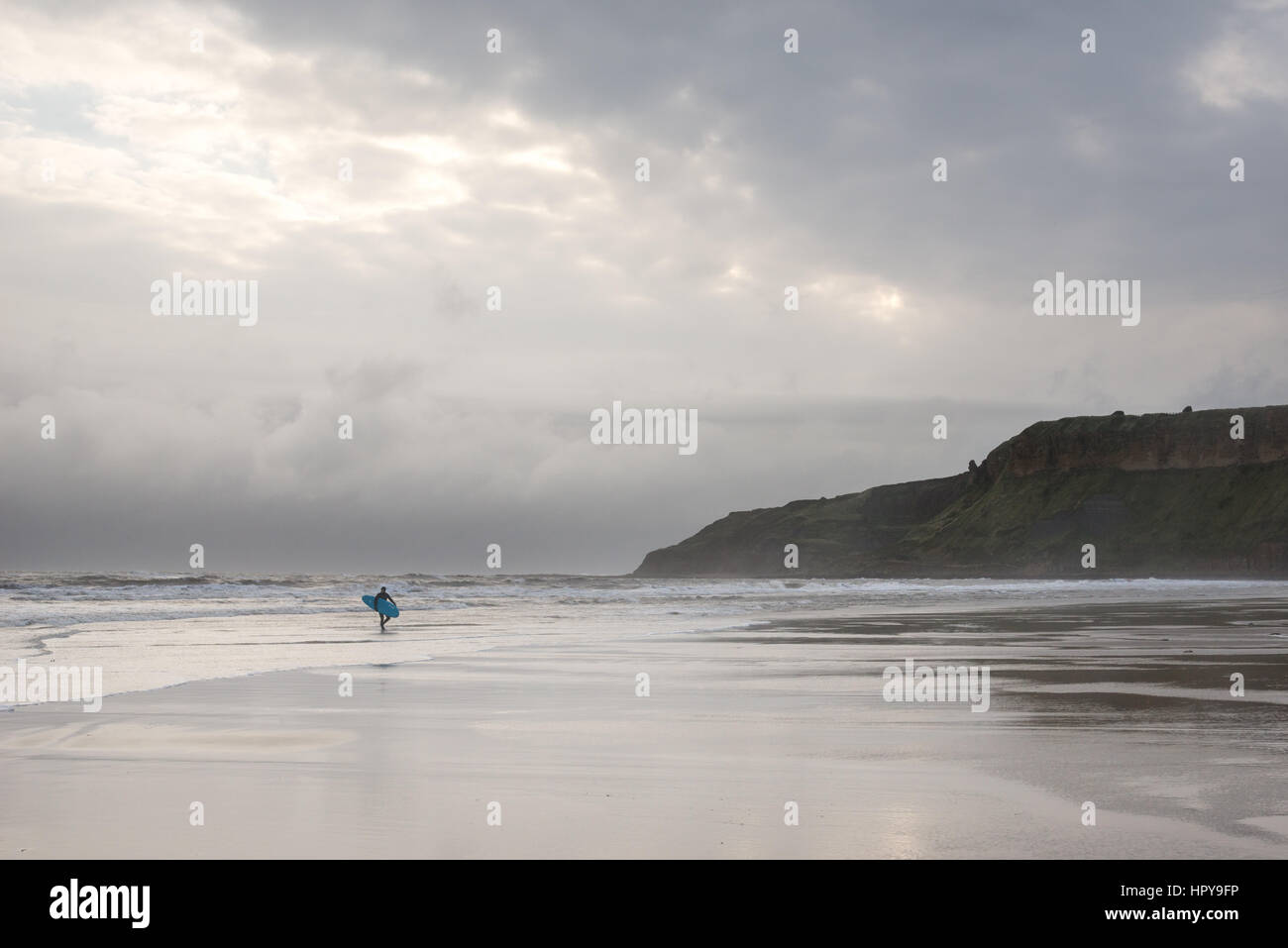 Surfer on the beach at Cayton bay near Scarborough, North Yorkshire, England. A popular surfing beach on the east coast of England. Stock Photo