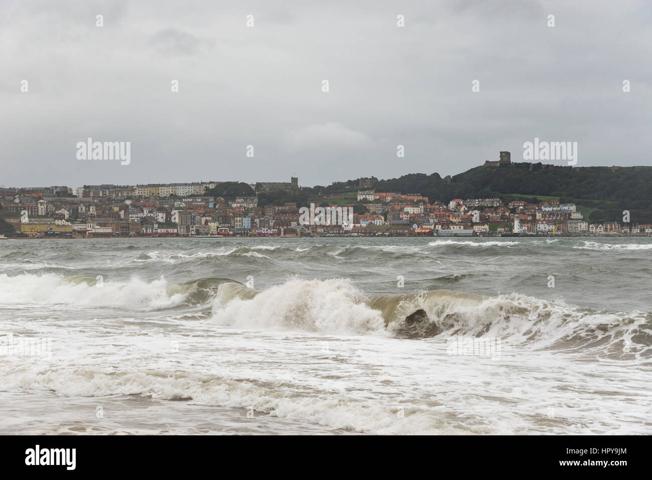 Rough sea at Scarborough, North Yorkshire on the east coast of England. View of the harbour and castle in the distance. Stock Photo