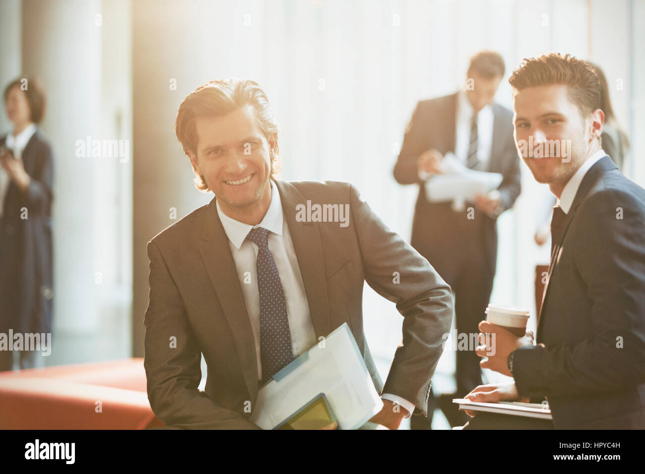 Portrait smiling businessmen in sunny office lobby Stock Photo - Alamy