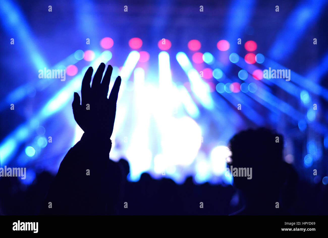 Raised hands at a live concert. Stage lights in the background Stock Photo