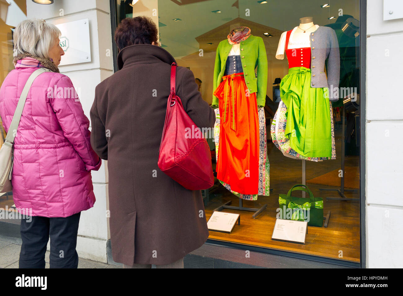 2  Elderly woman looking at traditional Bavarian dresses in fashion shop window, Munich, Upper Bavaria, Germany, Europe Stock Photo
