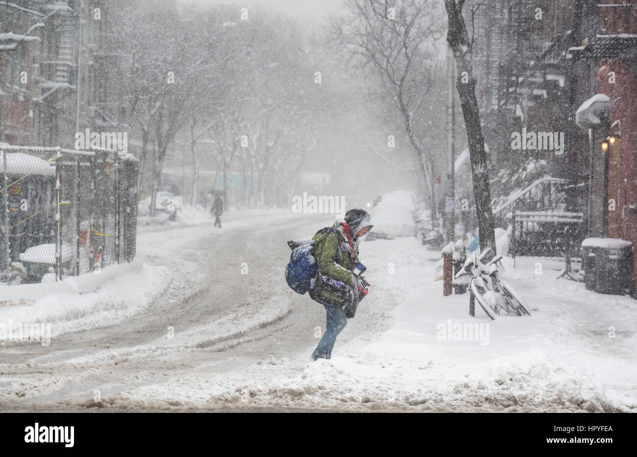 snow storm in new york, person crosses road with heavy bags Stock Photo