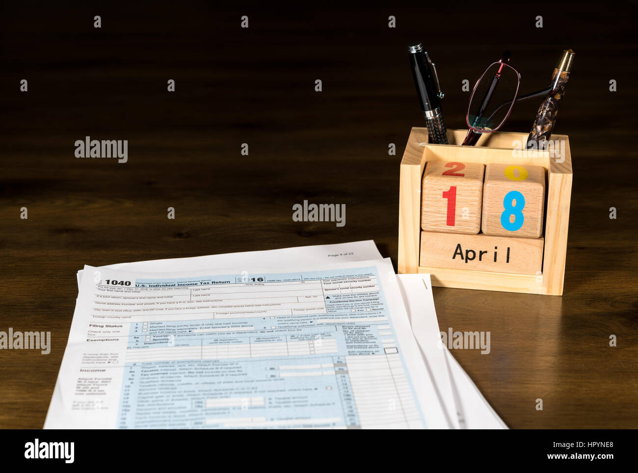 Wooden letters in calendar with Form 1040 income tax for 2016 showing tax day for filing is April 18 2017 Stock Photo