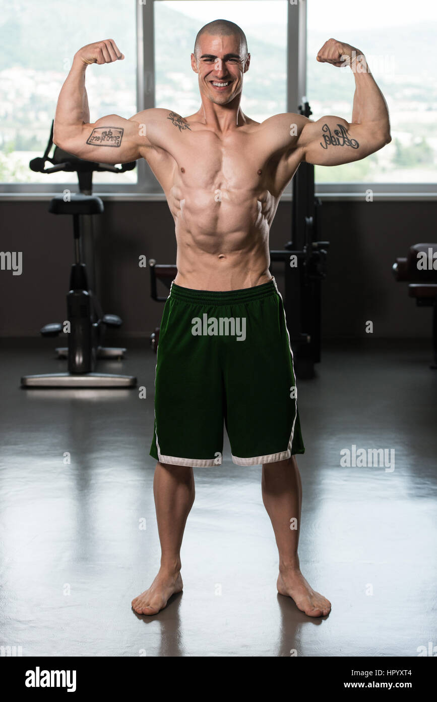 Portrait Of A Young Fit Man Showing Front Double Biceps Pose - Muscular Athletic Bodybuilder Fitness Model Posing Stock Photo