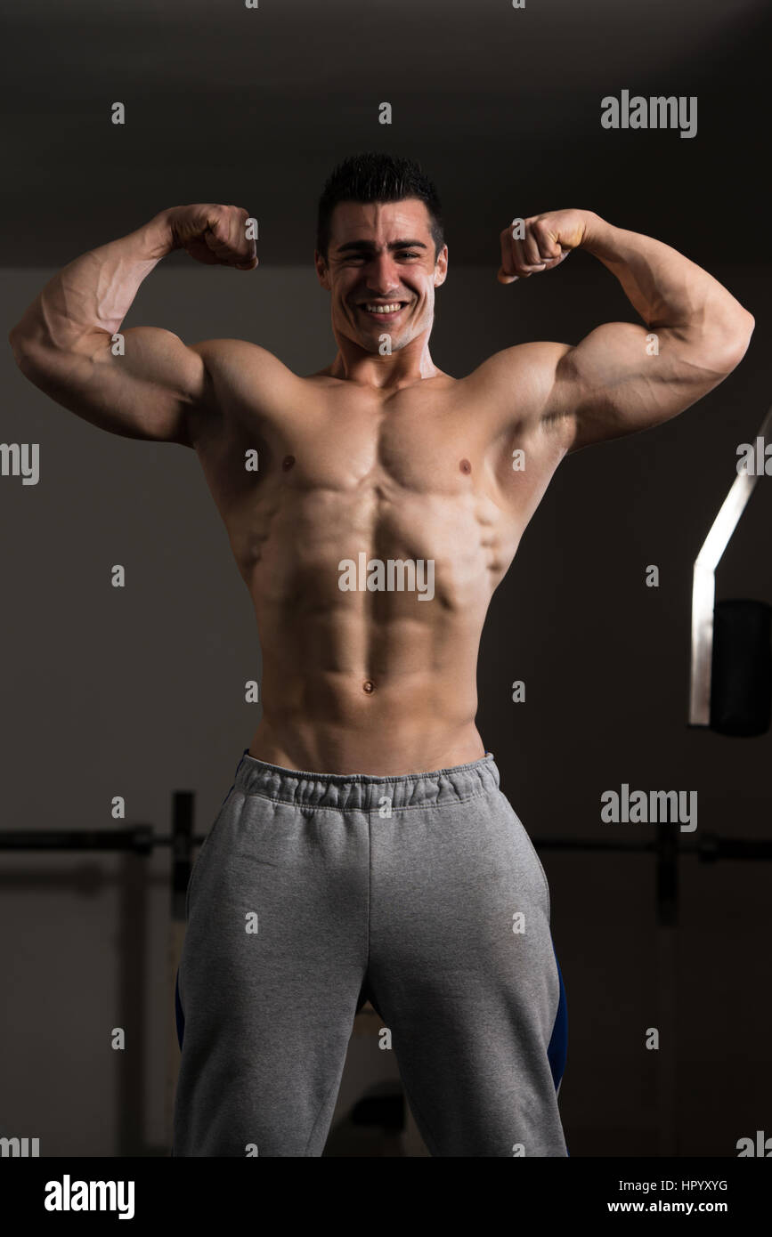 Portrait Of A Young Fit Man Showing Front Double Biceps Pose - Muscular Athletic Bodybuilder Fitness Model Posing Stock Photo