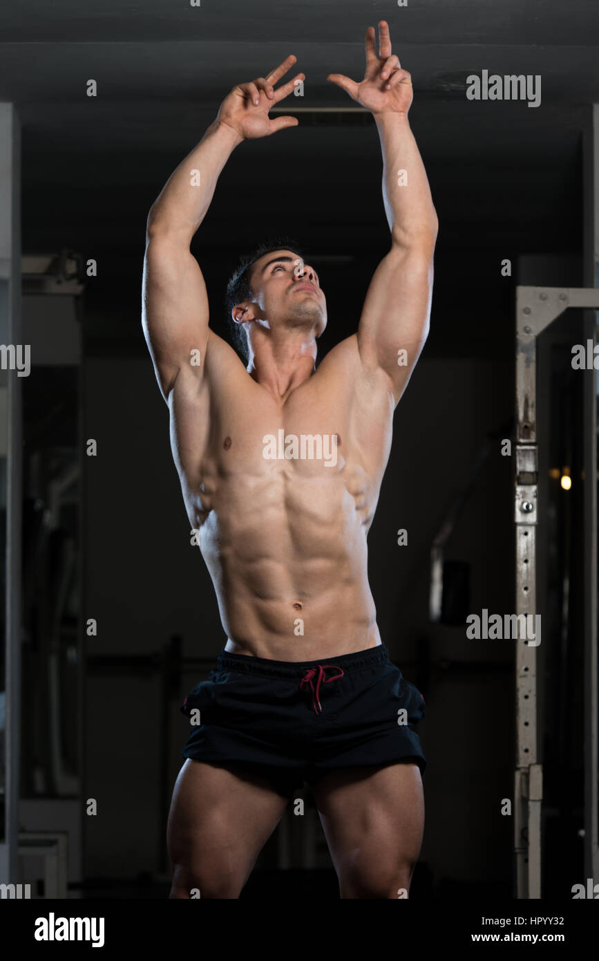 Young Man Standing Strong In The Gym And Flexing Muscles - Muscular Athletic  Bodybuilder Fitness Model Posing After Exercises Stock Photo - Alamy