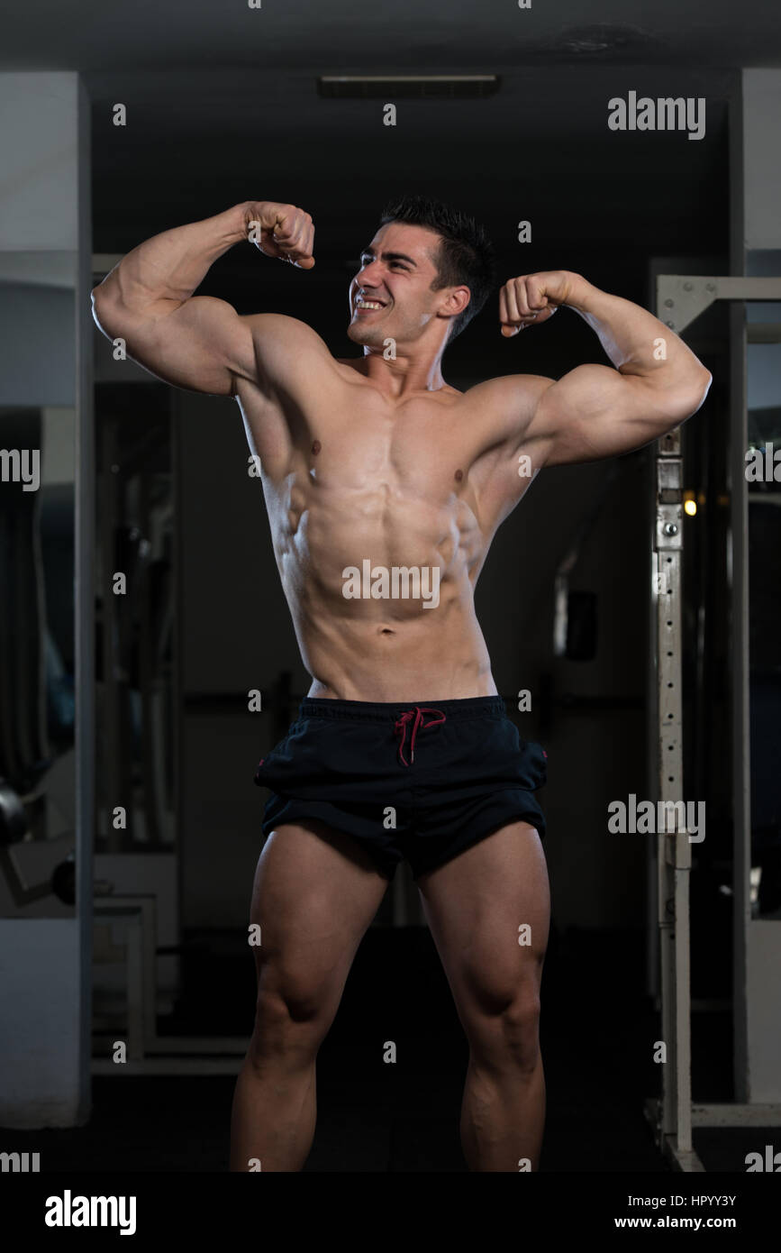 Portrait Of A Young Fit Man Showing Front Double Biceps Pose - Muscular Athletic Bodybuilder Fitness Model Posing Stock Photo