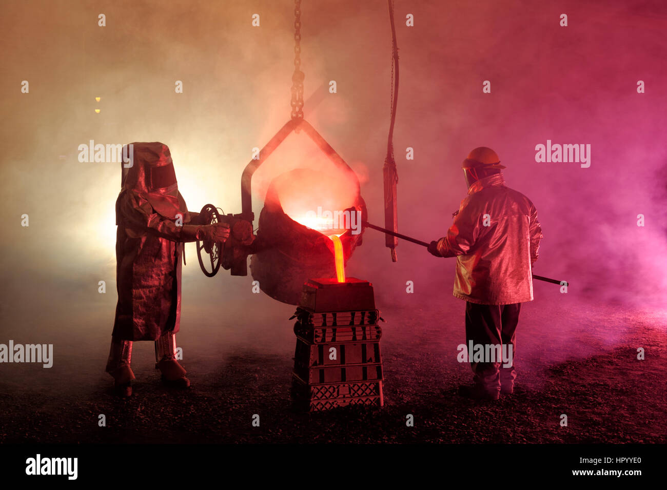 Pouring molten iron in a steel mill reenactment, metallurgical workers with ladle bucket, hot, smoky, and dangerous, Bethlehem, Pennsylvania, USA. Stock Photo