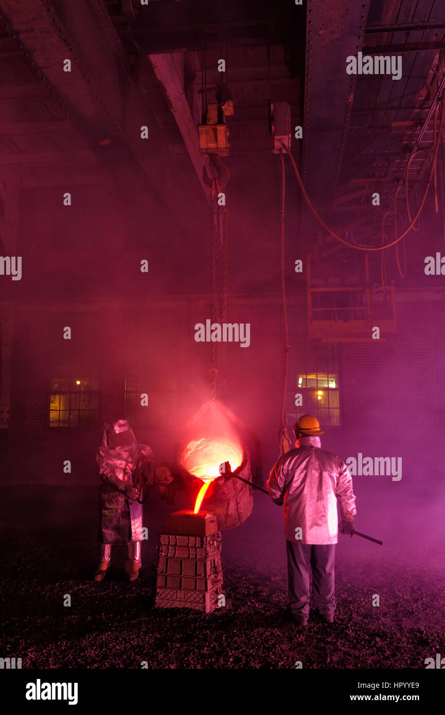 Pouring molten iron in a steel mill reenactment, metallurgical workers with ladle bucket, hot, smoky, and dangerous, Bethlehem, Pennsylvania, USA. Stock Photo
