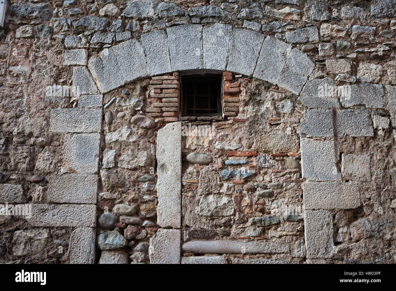 Medieval stone wall with inbuild arch and small window Stock Photo
