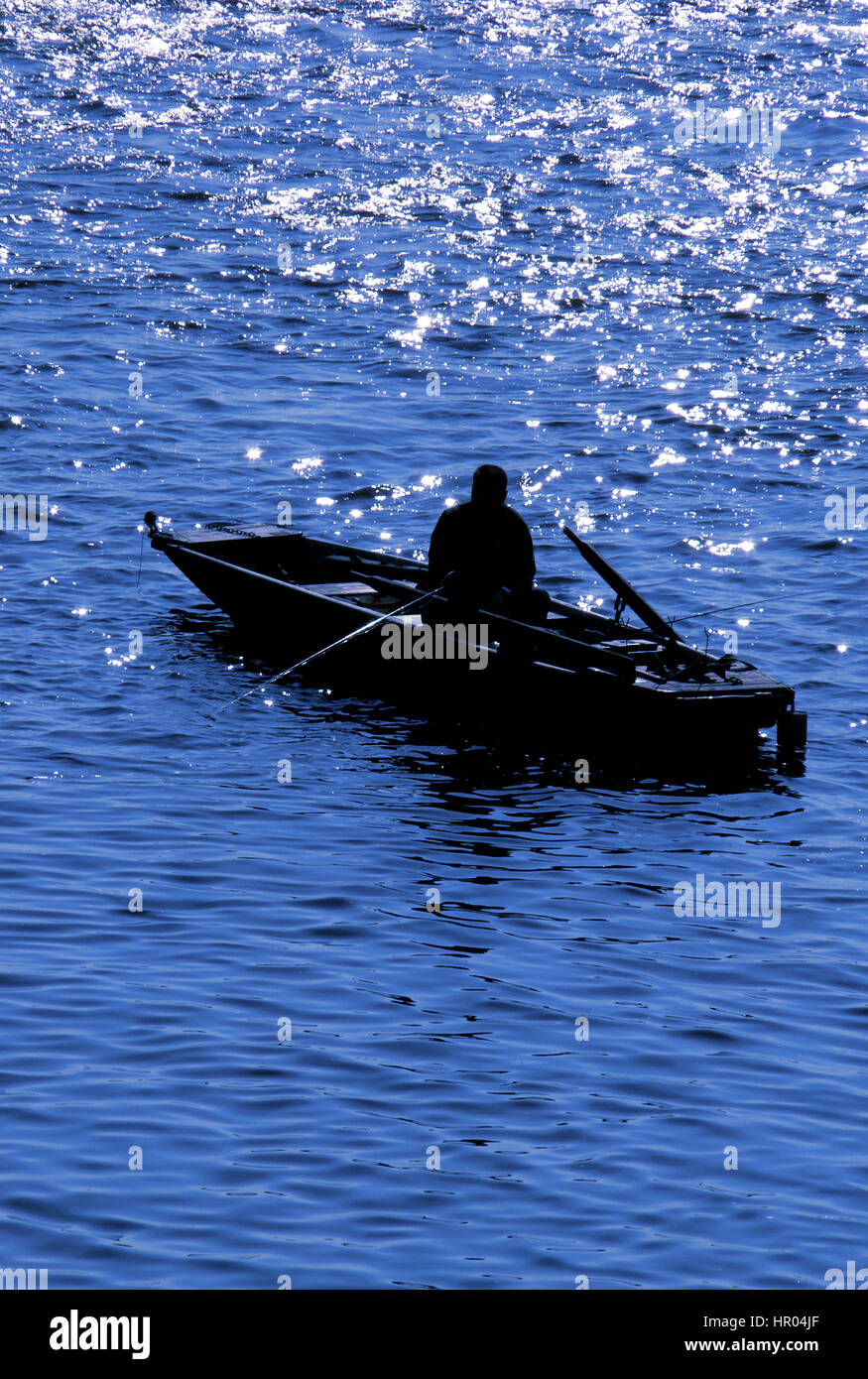 silhouette of a fisherman on a small boat fishing in the river Stock ...