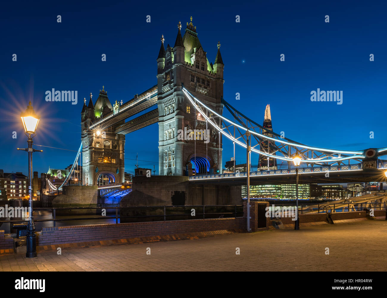 The lights come on at dusk on Tower Bridge on a calm but cold night in the capital city of London. Stock Photo
