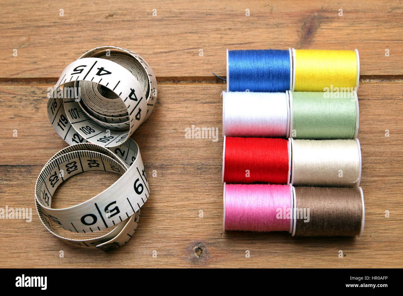 Multi-colored cotton reels and tape measure on a wooden sewing table Stock  Photo - Alamy