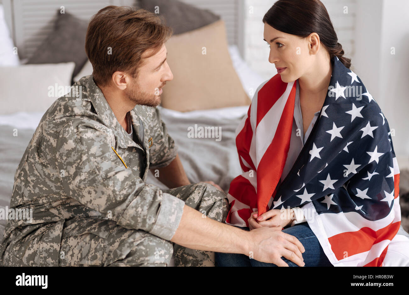 US army. Nice attractive brunette woman being wrapped in the us flag and looking at her husband while supporting him Stock Photo