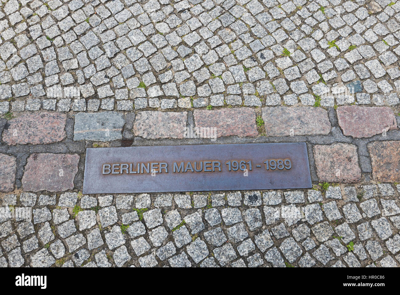 A memorial metal plaque on the road where the Berlin wall stood to divide East and West Berlin, Germany Stock Photo