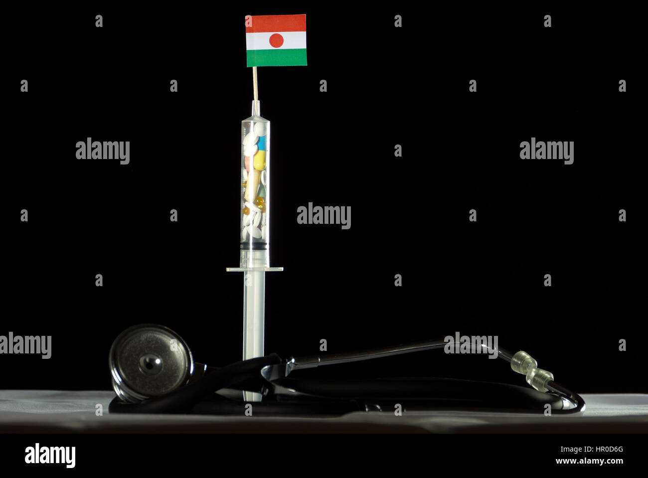 Stethoscope and syringe filled with drugs injecting the Nigerien flag on a black background Stock Photo