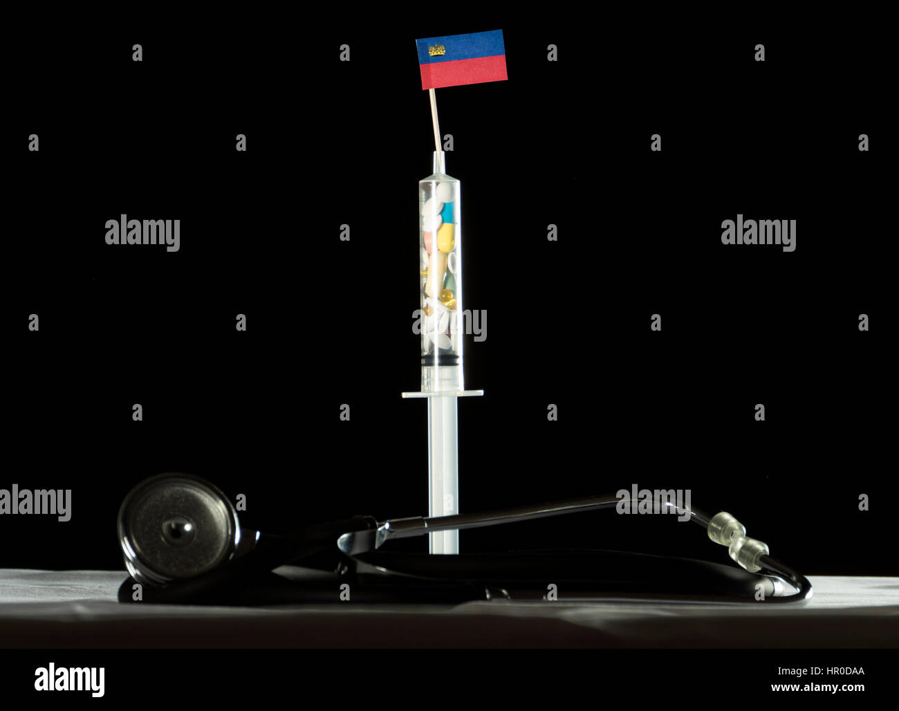 Stethoscope and syringe filled with drugs injecting the Liechtenstein flag on a black background Stock Photo