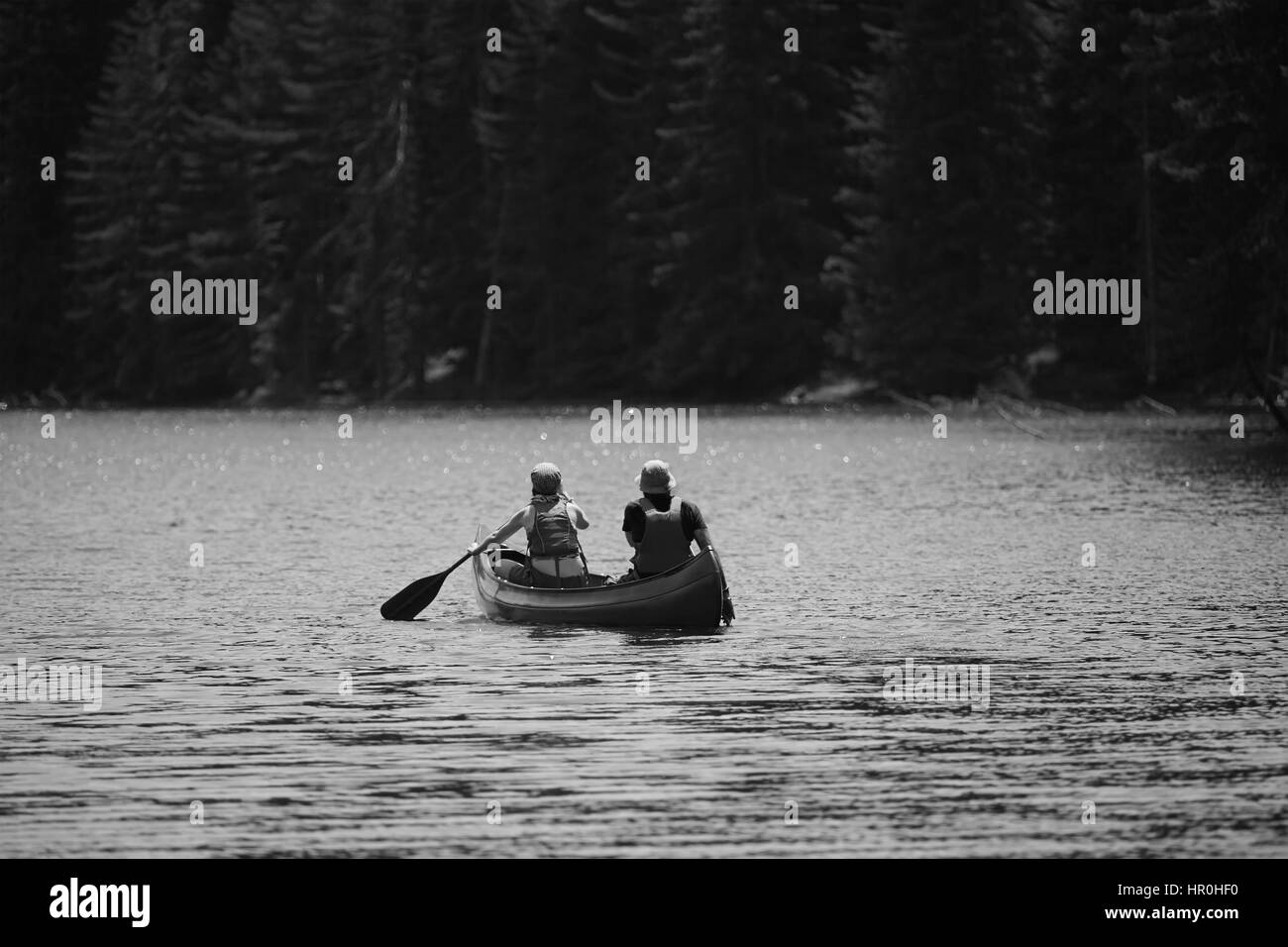 young couple with kayak in high mountain lake, black and white nature and human landscape Stock Photo