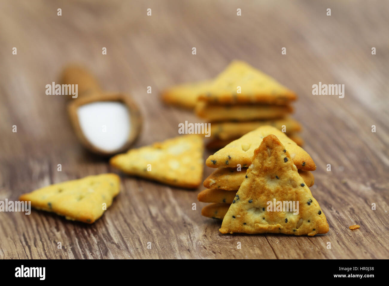 Salty snack triangles with poppy seed and sesame seeds on wooden surface Stock Photo