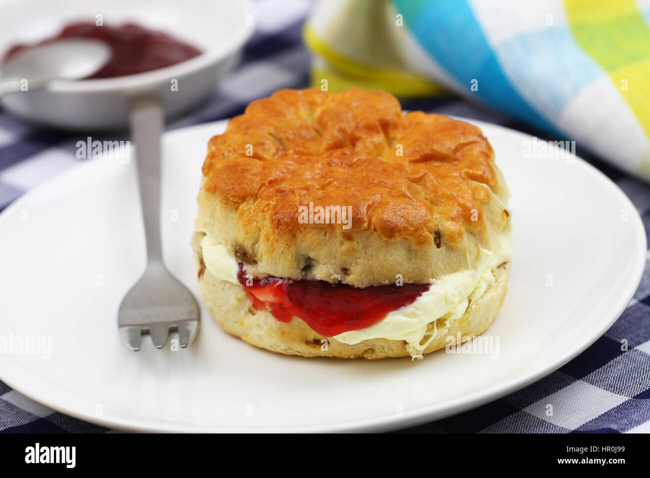 English scone with traditional clotted cream and strawberry jam on white plate Stock Photo