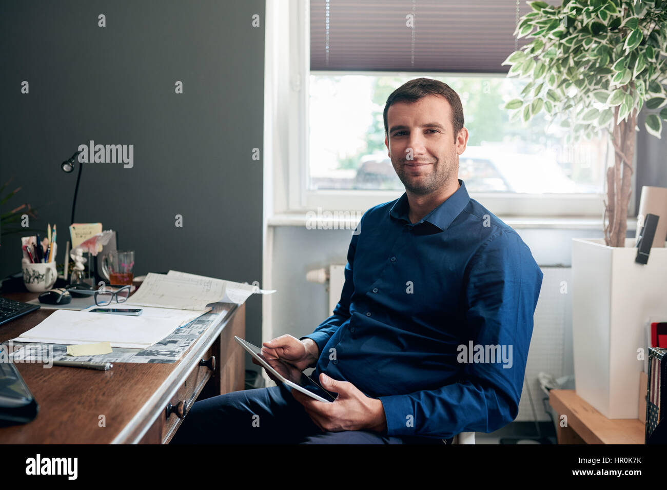 Portrait of a successful young businessman using a digital tablet while ...