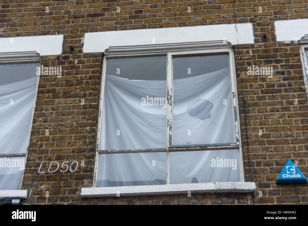 London, UK. 25th February 2017. A broken window at the first-floor LD50 gallery in Dalston where several hundred people from East London gather outside. They say the gallery s in one of London's more diverse areas has promoted fascists, neo-Nazis, misogynists, racists and Islamophobes, and the gallery, whose name refers to the dose of any substance required to kill 50% of those taking it, 'has been responsible for one of the most extensive neo-Nazi cultural programmes to appear in London in the last decade.' The protesters want the gallery to be closed. Credit: Peter Marshall/Alamy Live News Stock Photo