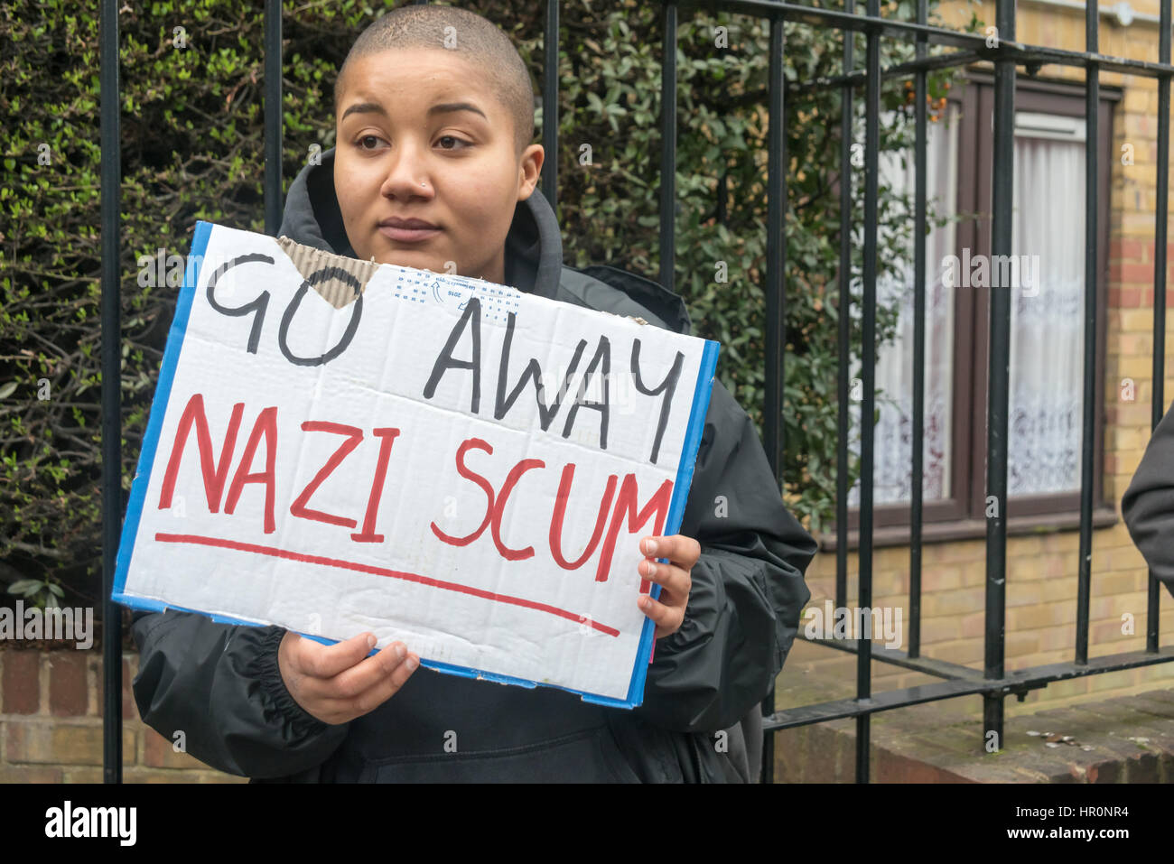London, UK. 25th February 2017. One of several hundred people from East London outside the LD50 gallery in Dalston holds a poster 'Go Away Nazi Scum'. Protesters say the gallery in one of London's more diverse areas has promoted fascists, neo-Nazis, misogynists, racists and Islamophobes and 'has been responsible for one of the most extensive neo-Nazi cultural programmes to appear in London in the last decade.' The protesters want the gallery to be closed. Credit: Peter Marshall/Alamy Live News Stock Photo