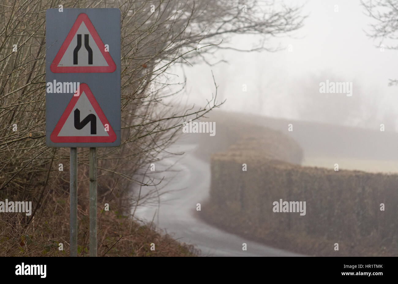 Road narrows and double bends, first to the left, on a road in Wales with light winter fog. Near the Glanusk Estate in Brecon National Park Stock Photo