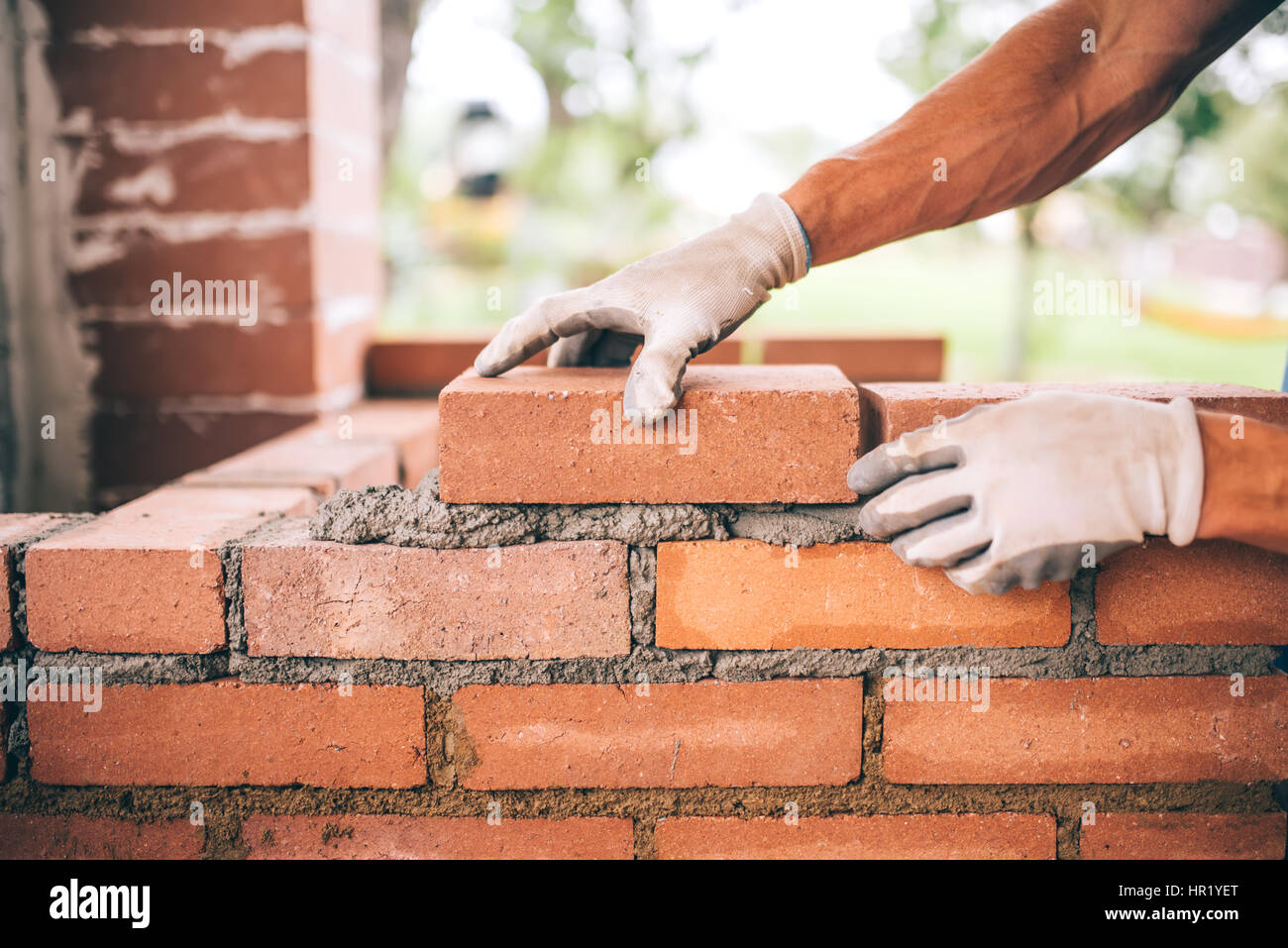 professional construction worker laying bricks and building barbecue in industrial site. Detail of hand adjusting bricks Stock Photo