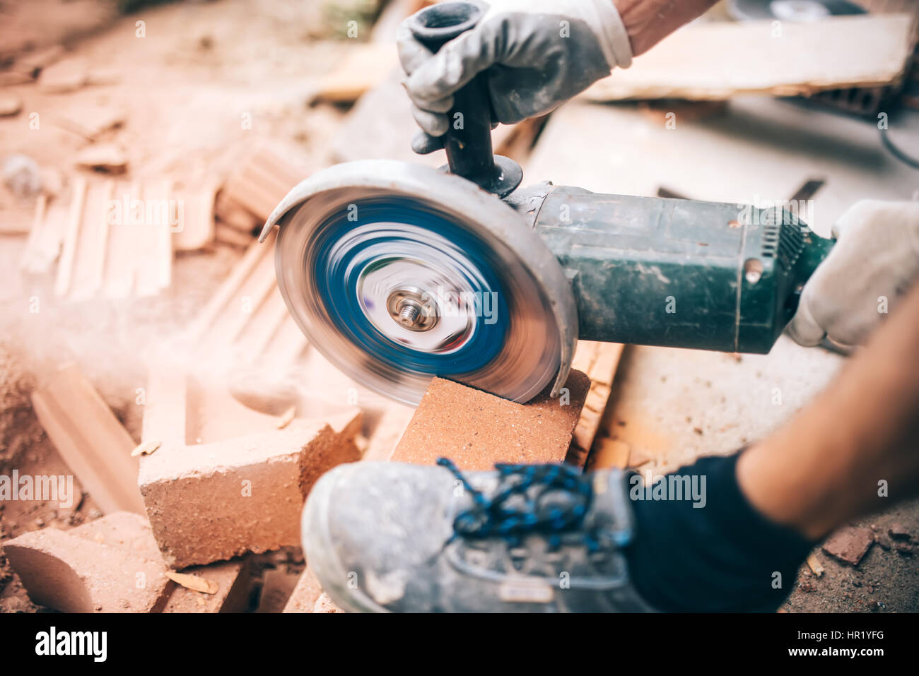 worker using grinder on construction site for cutting bricks, debris