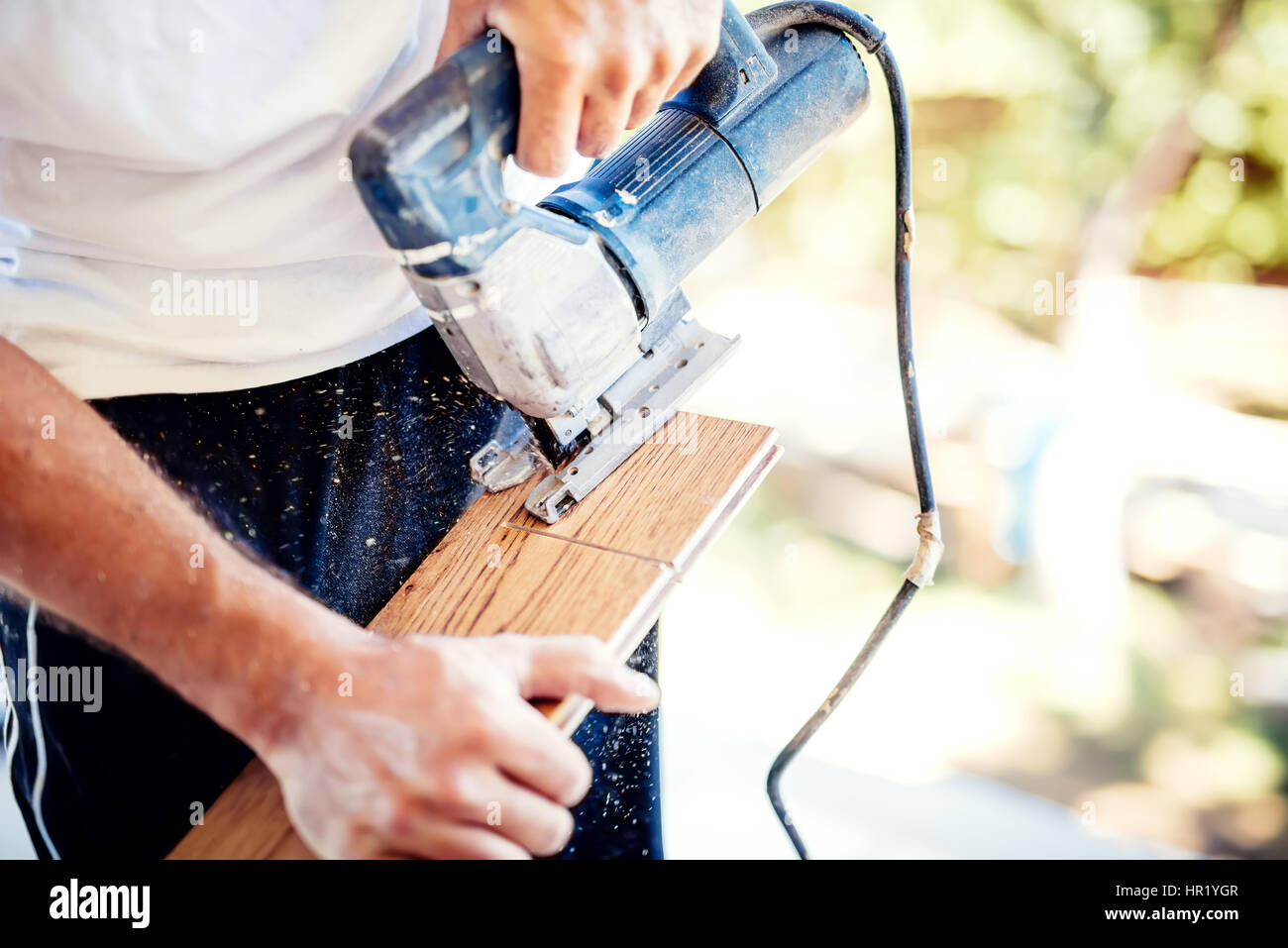 male worker cutting wood parquet using circular saw during home improvement works Stock Photo