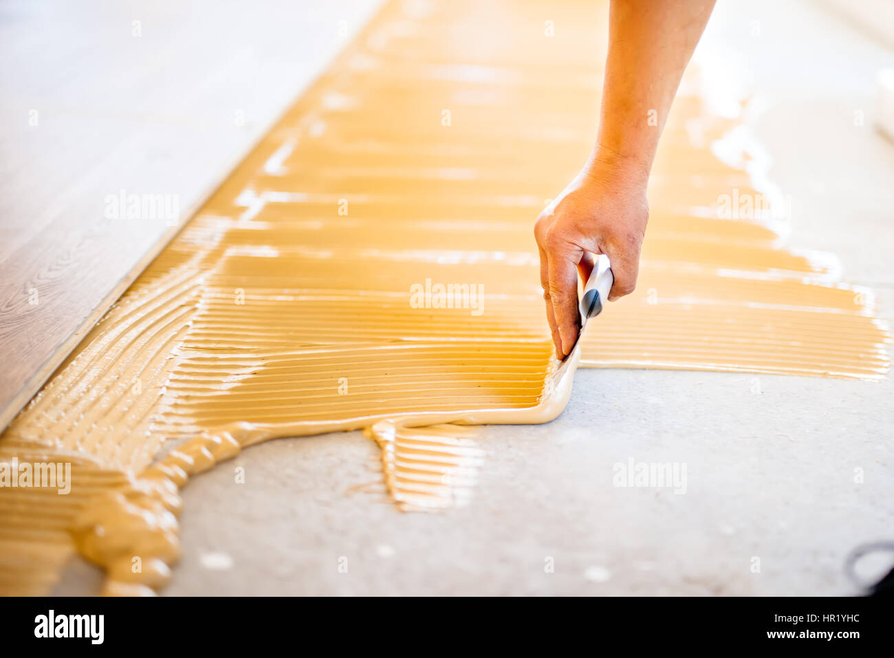 close-up of hand of worker adding glue during parquet installation Stock Photo