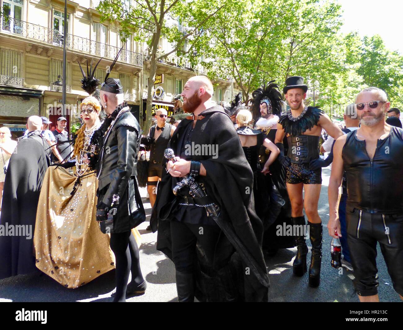 Paris Pride Parade 2015, Marche des Fiertés, matching group of participants wearing black leather, long gold gown. Blvd Saint-Michel. Paris, France. Stock Photo
