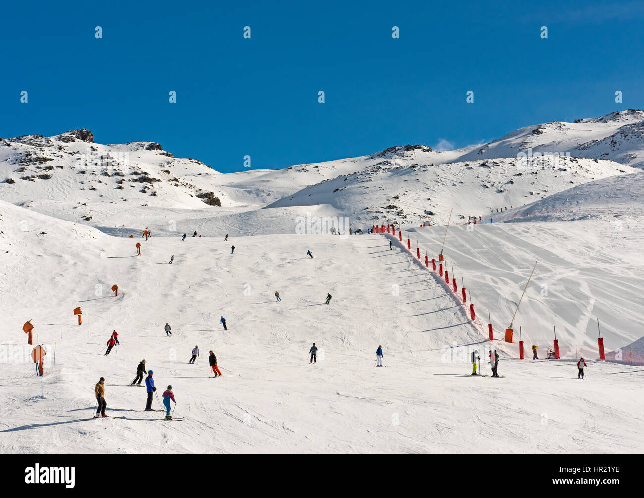 Skiers on a ski slope piste in winter alpine mountain resort Stock Photo
